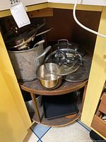 Various pots, pans and lids on lower cabinet shelf
