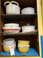 Cupboard shelves with multiple white, yellow and red-striped bowls and casseroles
