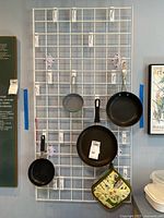 Overall lot: four frying pans, pot holder, metal grid rack