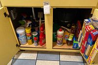View of cabinet showing assorted cleaning bottles, aerosols and wipes