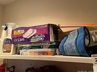 Shelf with Bona cleaner bottle, Swiffer WetJet box, wet mopping cloths box, Bona pad package, blue cloth, orange handle
