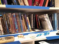 Shelf with approximately twenty assorted DVD cases including Outlander, Emma, Exodus, Civilization