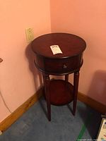 Full view of round wood accent table against wall