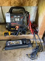 Front view of MotoMaster Eliminator 700A power pack, inverter, 12V adapter, charger and cables on shelf