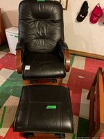 Front view of black faux-leather swivel recliner rocker chair with matching ottoman