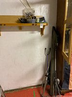 Full view showing rods in sleeves leaning against wall and shelf with tackle