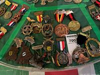 Overview of assorted medals, badges and ribbons on green surface