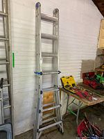 Full view of collapsed aluminum ladder leaning against wall