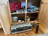 Wide view of cabinet with boombox, mini TV, organizer, batteries, tools and office supplies