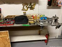 Workbench surface showing vise, tools, hardware trays and brass numbers