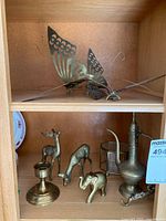 Shelf with butterflies on upper level and various brass items on lower