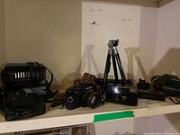 Shelf with Mamiya camera, lens, tripod, flash/light unit, compact cameras