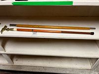 Two walking sticks laid on shelf showing full length and color difference