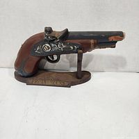 Full view of pistol decanter on wooden stand