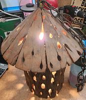 Light illuminated showing carved wood body and perforated top