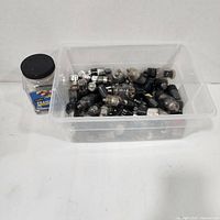 Overview of plastic tub filled with loose vacuum tubes and jar beside