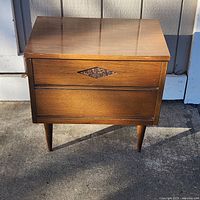 Front view showing drawers, diamond accent, tapered legs