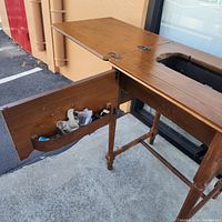 Open sewing cabinet showing interior cut-out and side accessory bin