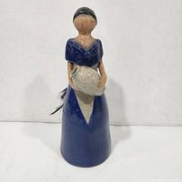 Front view of ceramic figurine showing dress color and jug