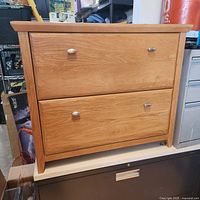 Front view of solid wood two-drawer locking cabinet with brushed metal pulls