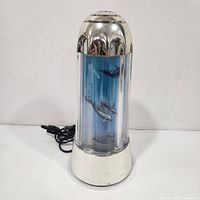 Lamp unplugged showing chrome housing and dolphins visible inside