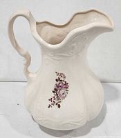 Front view of cream ironstone pitcher showing floral decal and scrollwork