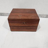 Closed wooden music box front view with small winding hole