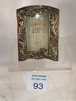 Full view of ornate copper dragon picture frame on display stand