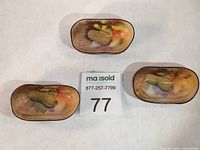 Top view of three miniature peanut dishes showing hand-painted interiors