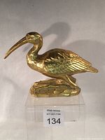 full view of gold crane statue on clear stand with lot tag