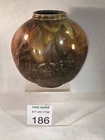 Full front view of spherical raku vase on stand