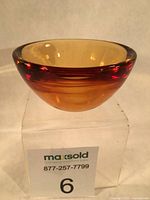 Oblique view showing amber-to-red layered glass bowl atop stand