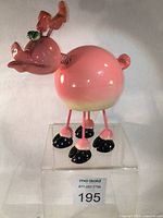 Full view of Exhart pink wobbly pig figurine on clear display block