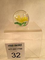 Full view of spherical glass paperweight showing chrysanthemum flower inside