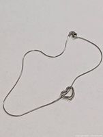 Full view of thin gold anklet with heart accent and clasp