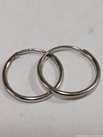 Pair of thin round 10K gold hoop earrings on white background