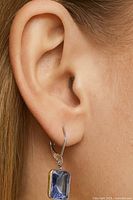 Earring worn on ear showing size, drop style and blue sapphire