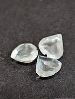 Three loose pear-cut aquamarines on dark background