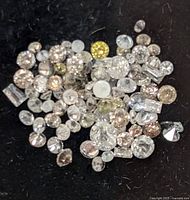Pile of assorted loose faceted diamonds showing various cuts and colours