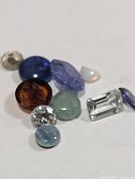Group of ten assorted loose gemstones of various colours and cuts on white background