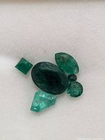 Loose emerald gemstones on white background showing shapes and color