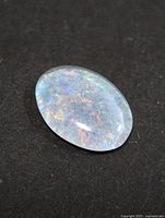 Oval opal triplet loose stone on black background showing play of colour