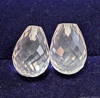 Pair of faceted teardrop rose quartz gemstones on dark background