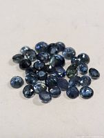 Pile of round faceted blue sapphires on neutral surface