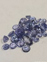 Scatter of loose faceted tanzanite stones on surface