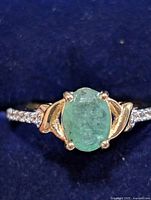 Front view showing green oval center stone, gold-tone shoulders and CZ accents