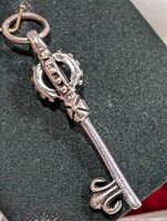 Key-shaped silver pendant on dark background