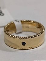 Silver band ring showing bezel-set sapphire and braided edges