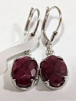 Front view of earrings showing ruby faces and leverback mounts