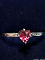 Front view showing heart-shaped pink stone and silver band